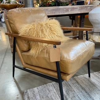 Light brown leather side chair with fluffy decorative pillow at Pottery World in Rocklin, California