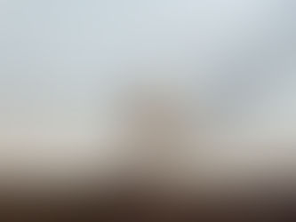 View through a jagged hole in glass, showing an abandoned lot with scattered debris. Suggesting being emotionally broken