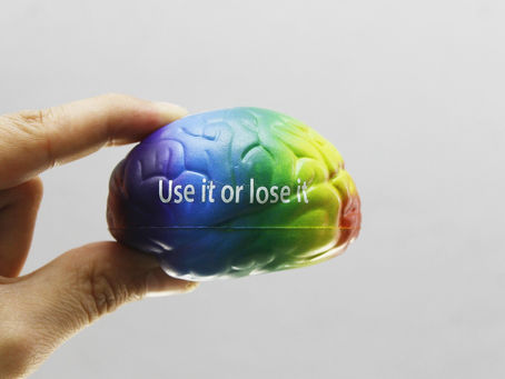 Hand holds a rainbow-colored brain-shaped object, illustrating emotional intelligence