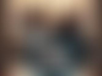 A concerned couple on a sofa watch a laptop video call at sunset, papers on table. City skyline view in background.