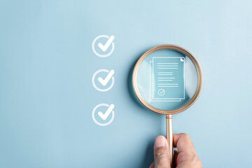 Hand holding magnifying glass over a checklist icon and document on a blue background. Three checkmarks are visible, symbolizing 2026 Real estate checklist