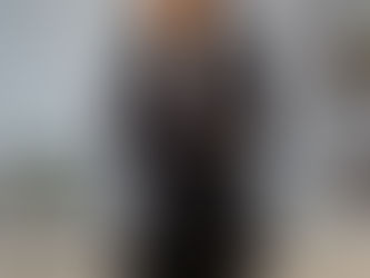 Smiling woman stands confidently in an office, suggesting job satisfaction.