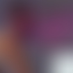 Woman in white sportswear uses breathing mask on exercise bike; man in background looks at data on screen. 