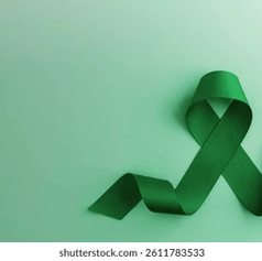 Green ribbon and stethoscope on a light green background. The ribbon is looped, symbolizing mental health awareness. No text present.