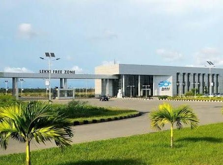 Lekki Free Zone entrance with modern gray building, palm trees and green lawn under a clear blue sky.