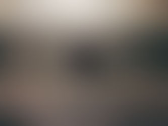 Person sitting against a concrete wall, arms hugging knees, in a dimly lit and empty room, conveying a mood of anxiety and introspection.