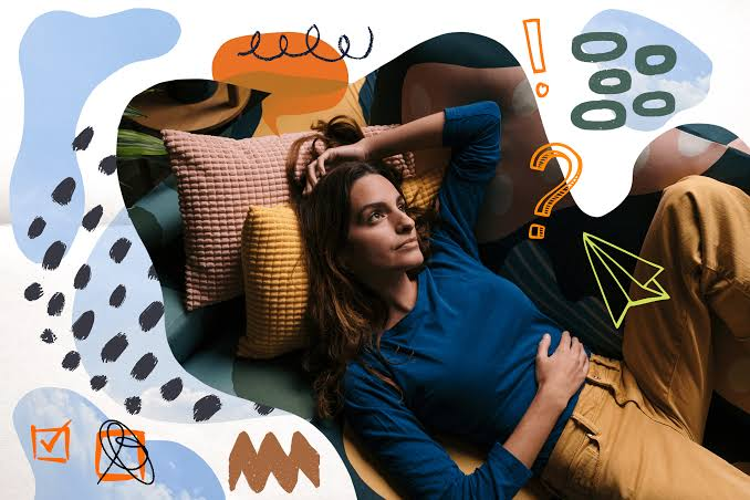 Woman reclines on a couch with pillows, wearing a blue top and tan pants, surrounded by colorful doodles and question marks.