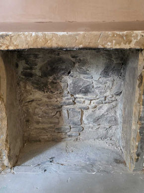 Worker applying plaster to interior wall with ladder and tools, documenting skilled craftsmanship in renovation.