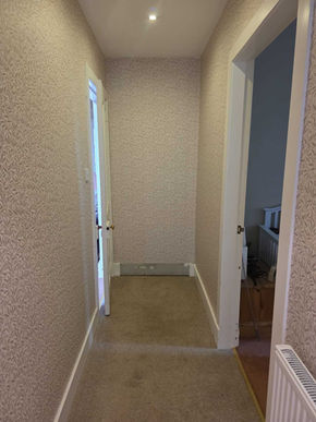 Fresh plaster being smoothed on interior wall beside fireplace, highlighting precision and professional renovation process.