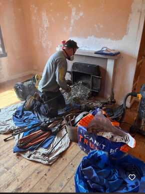 Person working indoors with tools and materials spread across a tarp, actively engaged in remodeling and construction tasks.