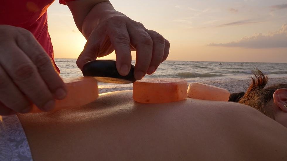 Hot stone massage therapy on a back at sunset