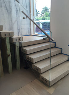 Glass railing with a stainless handrail on a floating stone stair