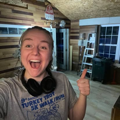 Leah smiling and giving a thumbs up in front of art studio