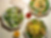 Table set with plates of fresh salad and two small bowls of dipping sauce, arranged for sharing