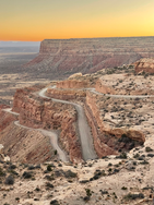 Winding road through West USA desert canyons at sunset.