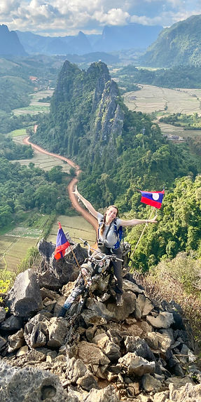 Woman holding Laos flag at the top a mountain in Laos