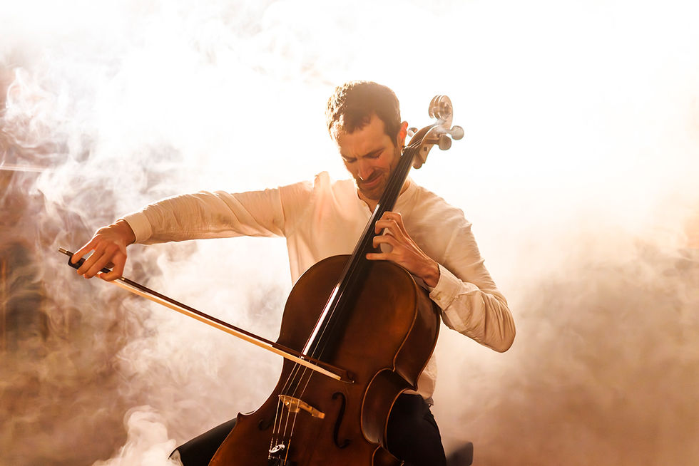 Ivan Nogueira op Cello in een witte blouse speelt gepassioneerd cello in een mysterieuze, rokerige omgeving. De sfeer is intens en expressief.