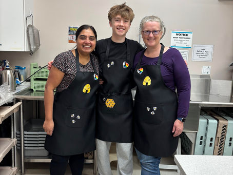 Three people with beehive aprons on in a commercial kitche