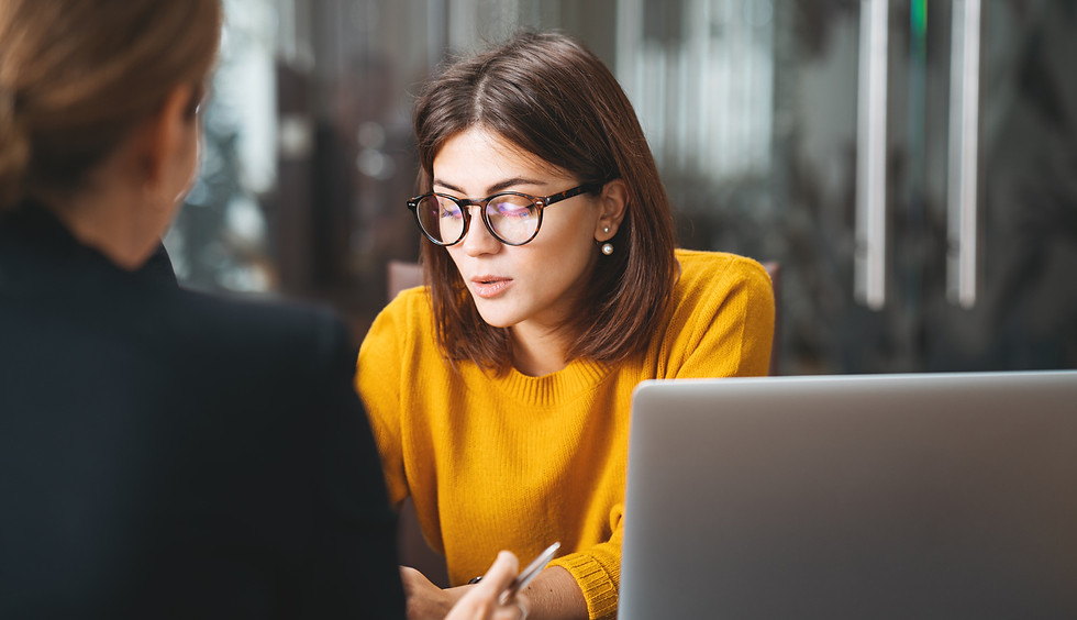 Woman discussing something with a client sitting across th desk from her.