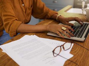 A woman in an orange shirt typing on the computer.