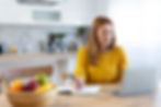 Woman in kitchen sitting at her computer.