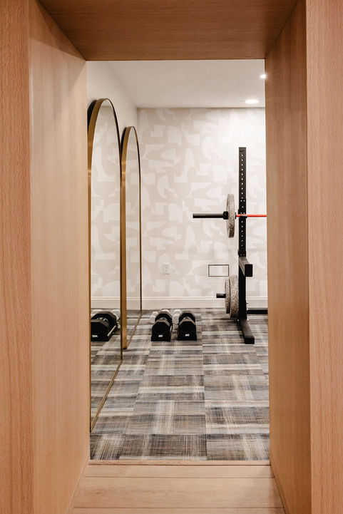 Home gym with mirrors and weightlifting equipment.