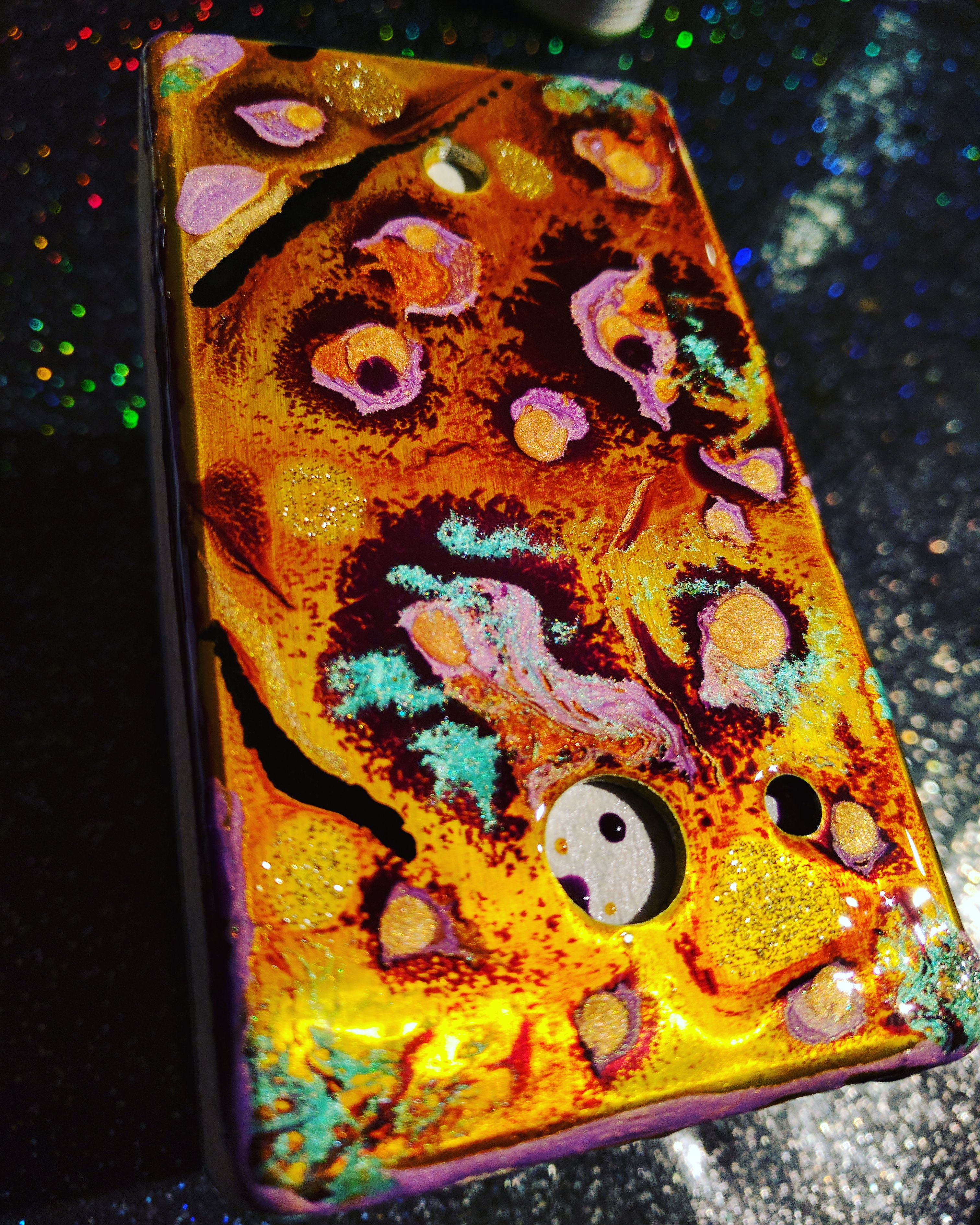 Drilled enclosure painted with a swirly pattern of red, orange, gold and purple.