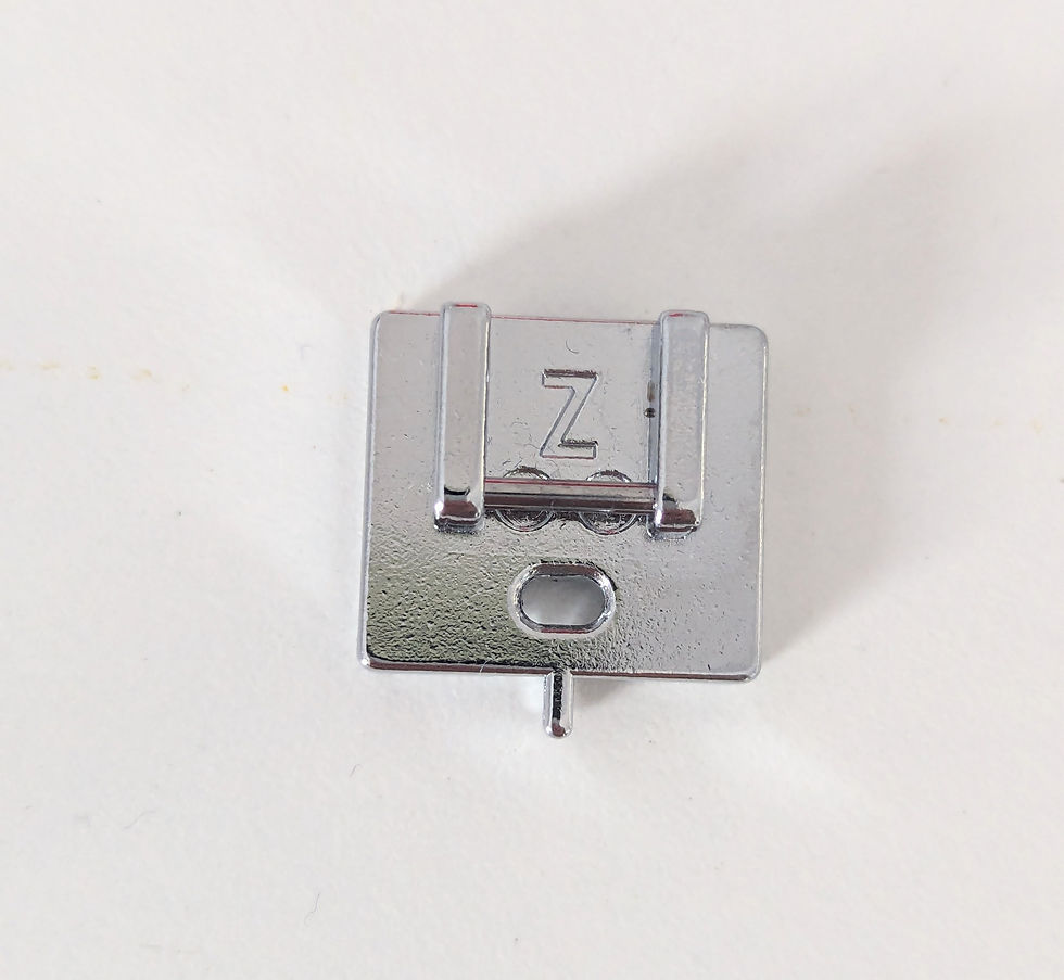 A concealed zip foot from a sewing machine on a white surface