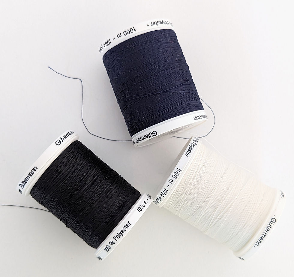 Three thread reels on a white surface, one black, one navy blue and one white
