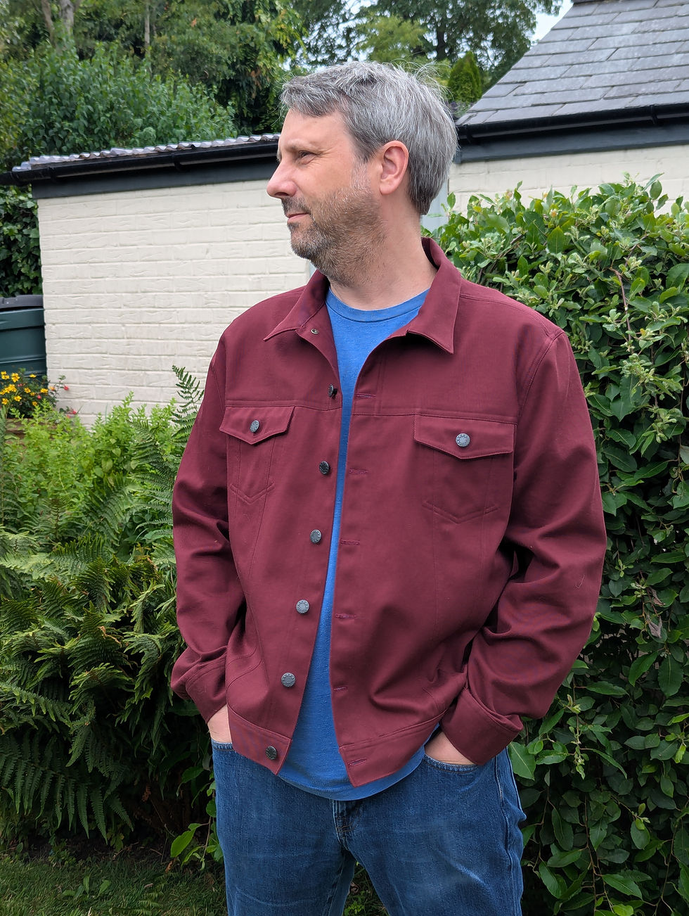 A man standing in a garden wearing a burgundy denim jacket made from Simplicity S8845
