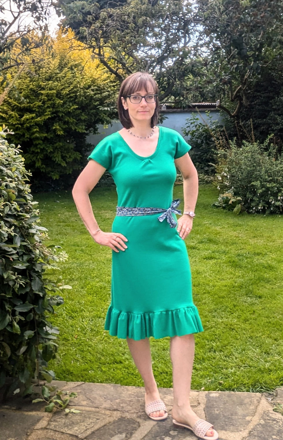 A woman wearing a green dress with a blue belt