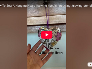 A handmade hanging heart in a floral fabric hanging from a drawer with a hand behind it