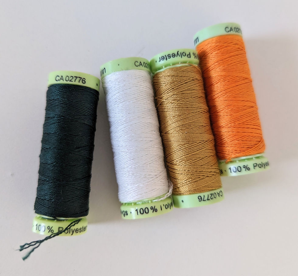 Four top stitching reels of thread on a white surface, forest green, white, beige and orange in colour