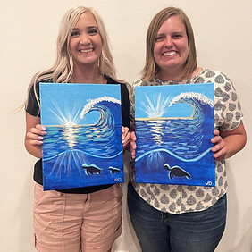 Two friends holding their painting of a sea turtle