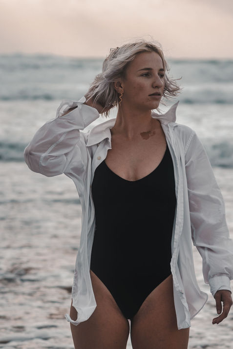 Femme à la plage lors d'une séance de portrait, portant une chemise blanche et un maillot de bain