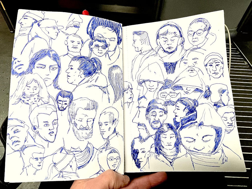 a hand holding a Sketchbook with blue ink fountain pen drawings of diverse human faces, some with hoodies, on a train. The background shows part of a floor and seat of the public transportation BVG in Berlin