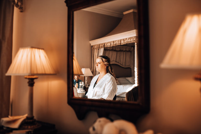 Bridesmaid has her make-up applied as we look through a mirror on the wall.jpg