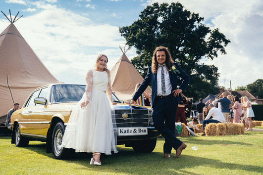 wedding couple with wedding car in front of wedding tipi