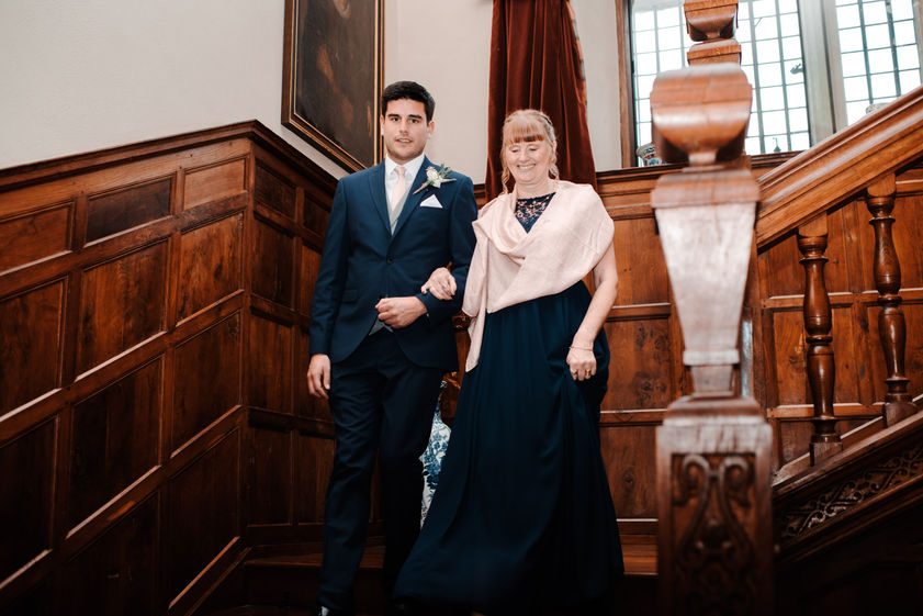 Groom and his mother walk together down a wooden staircase.jpg