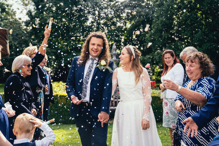 wedding couple walking through confetti whilst laughing