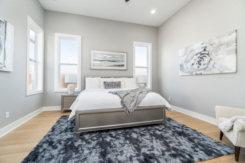 Spacious primary bedroom with hardwood floors and natural light in Northwest Arkansas house for sale.