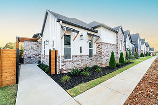 Single-story home with white siding, brick accents, and landscaped yard in Northwest Arkansas.