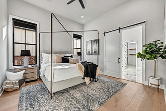 Stylish bedroom with canopy bed, barn door, and large windows in a Northwest Arkansas custom home.