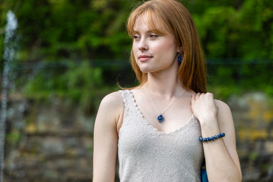Kadey Copeland wearing a lapis lazuli diamond pendant, rectangular dangle earrings, and 10mm lapis bracelet at Twin Springs Park.