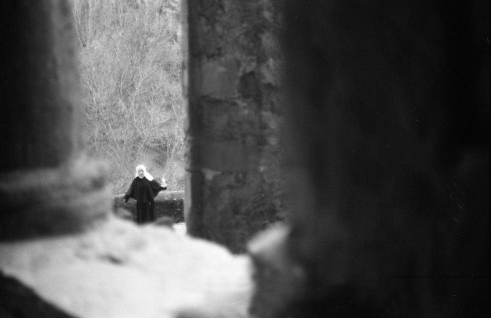 Nun seen through a dark opening, atmospheric photography.