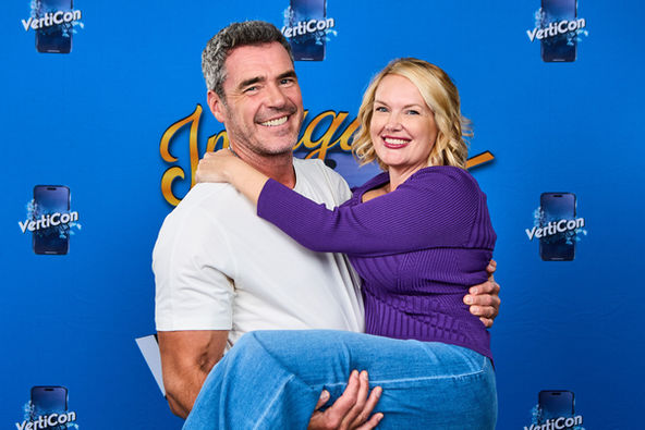 male actor and female fan posed in from of event backdrop, fan held in actors arms.