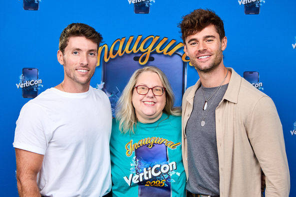 Two male actors on either side of female fan, posed for professional photo in front of event backdrop.