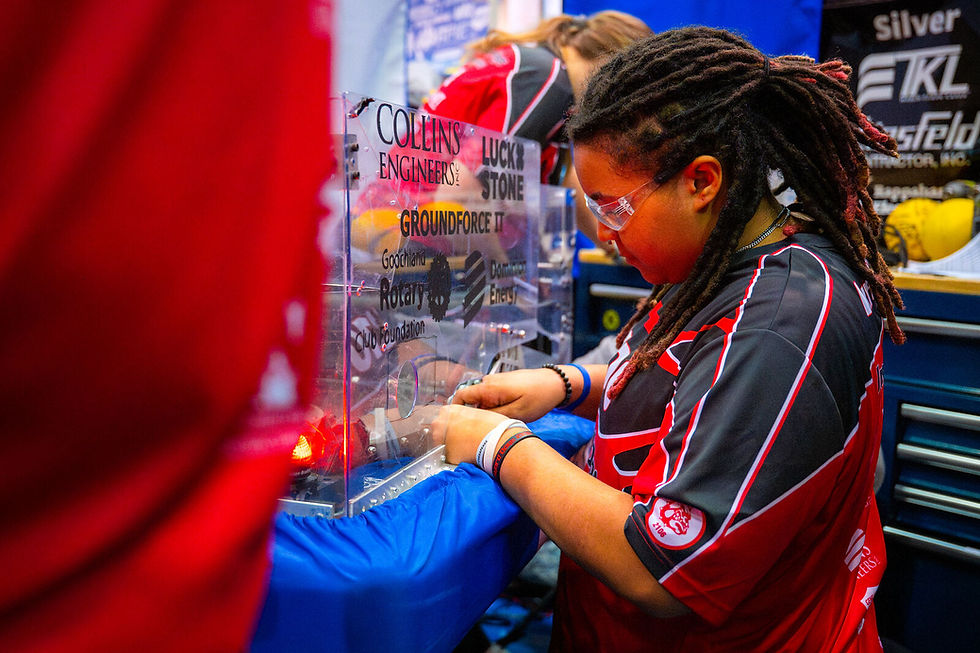 A student works on her team's robot in the pits