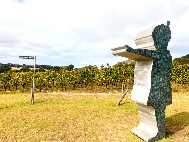 Sculpture with sign pointing towards vineyards, with text