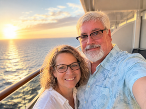 Couple relaxing on a cruise ship balcony at sunrise overlooking the ocean during a peaceful cruise vacation.